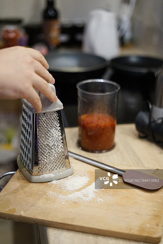 男人在木板上为意大利碳ara面做番茄酱和磨碎的奶酪，家庭烹饪。图片素材