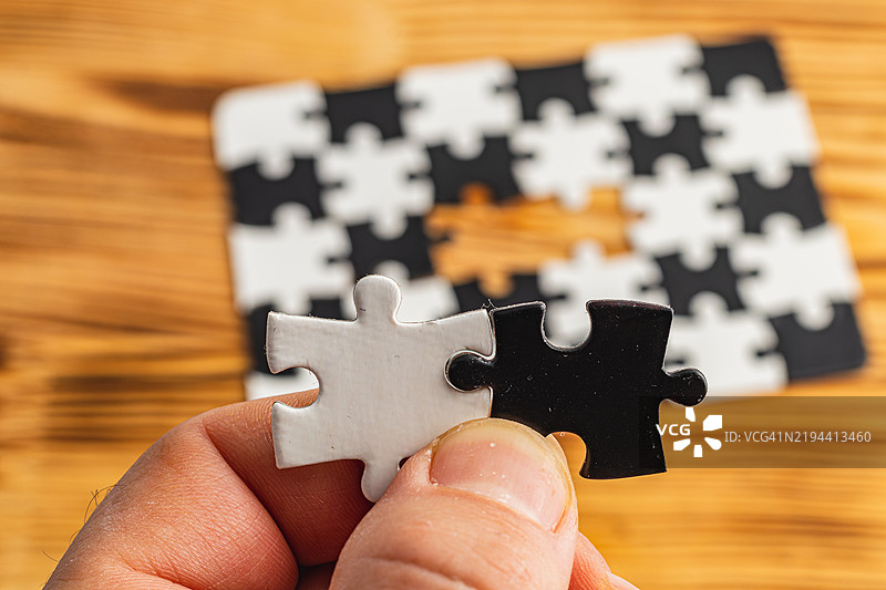 手握黑白拼图，象征着艰难的选择。图片素材