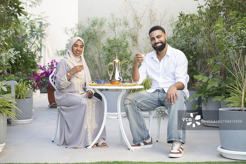 阿联酋夫妇在露台上享受传统阿拉伯茶，面带微笑地看向镜头图片素材