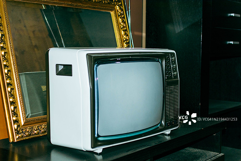旧款便携式电视机旁边显示静态画面的金色框架图片素材