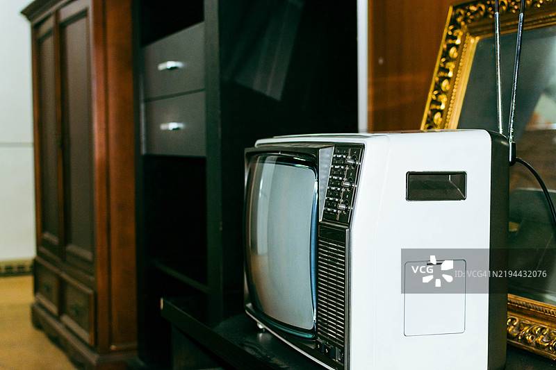旧电视机摆放在家具上，旁边有一个相框图片素材