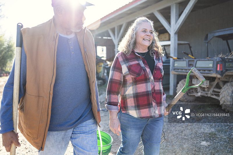 一对年长的男女农民在谷仓前微笑着散步图片素材
