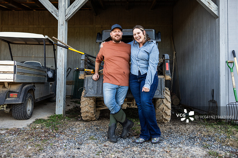 年轻的农夫夫妇在谷仓前微笑的肖像图片素材