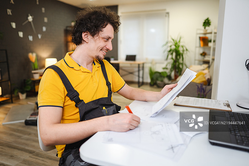 维修工在家中根据文件上的说明进行工作图片素材