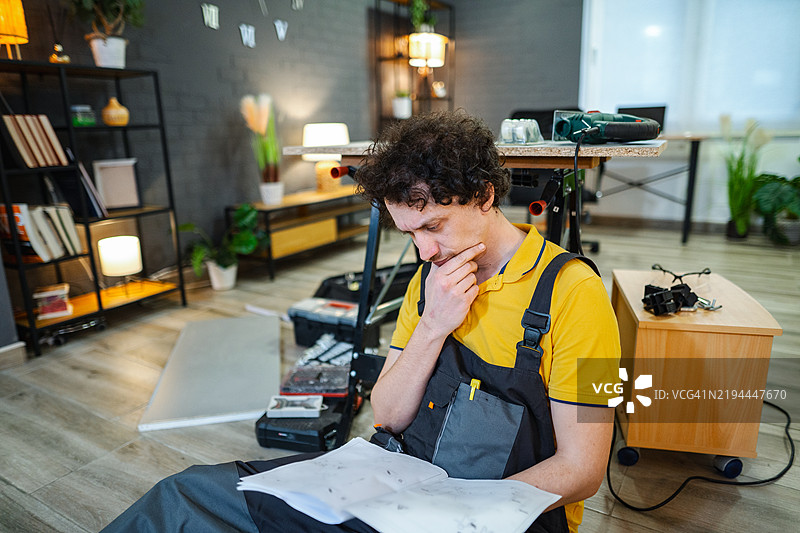 修理工在阅读说明书并思考房屋修缮项目图片素材