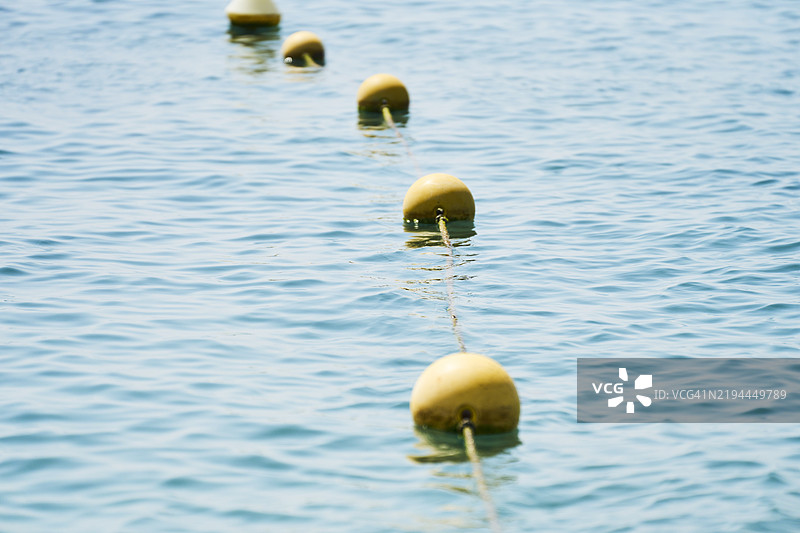 黄色浮标漂浮在平静的海面上，形成了一条分界线图片素材