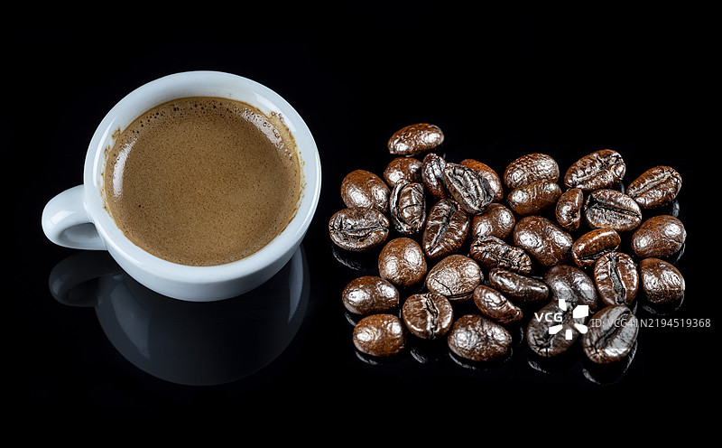 浓缩咖啡杯与烘焙的罗布斯塔咖啡豆在黑色背景上的倒影。图片素材