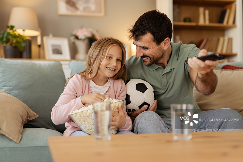爸爸和小女孩在家里一起观看足球比赛，增进感情图片素材