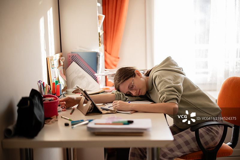 疲惫的女孩趴在桌子上睡觉图片素材