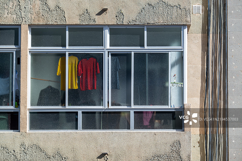 五彩斑斓的衣服在住宅楼的窗户内晾晒图片素材