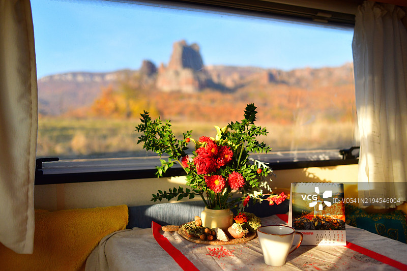 房车内部，桌子上有咖啡和花卉，窗外美丽的景色。图片素材