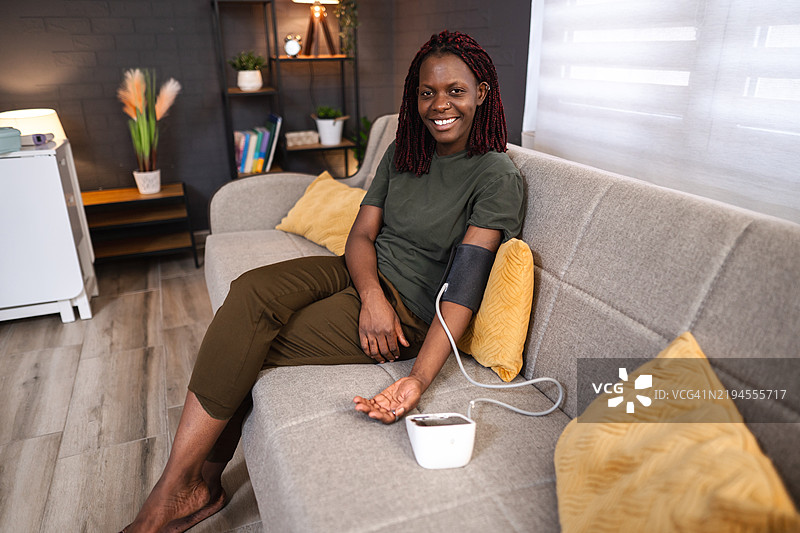 年轻女性在沙发上自测血压图片素材