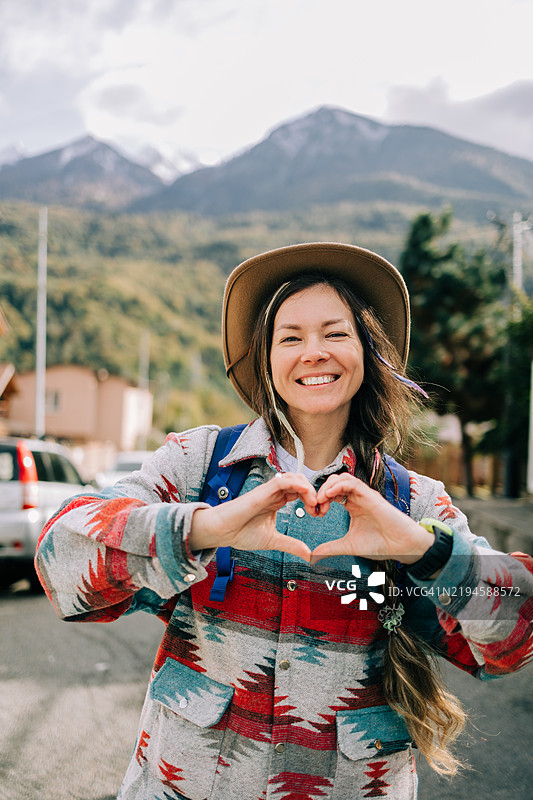 微笑的女性游客在山景中用双手做出心形手势图片素材