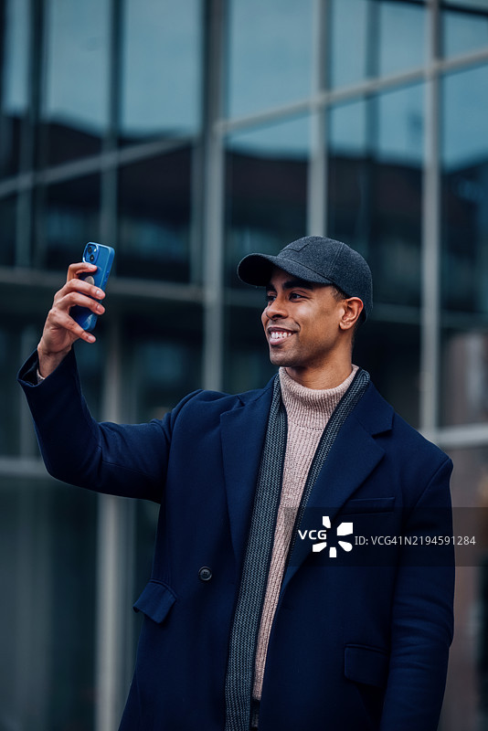 在现代城市环境中穿着时尚服装的男子户外自拍图片素材
