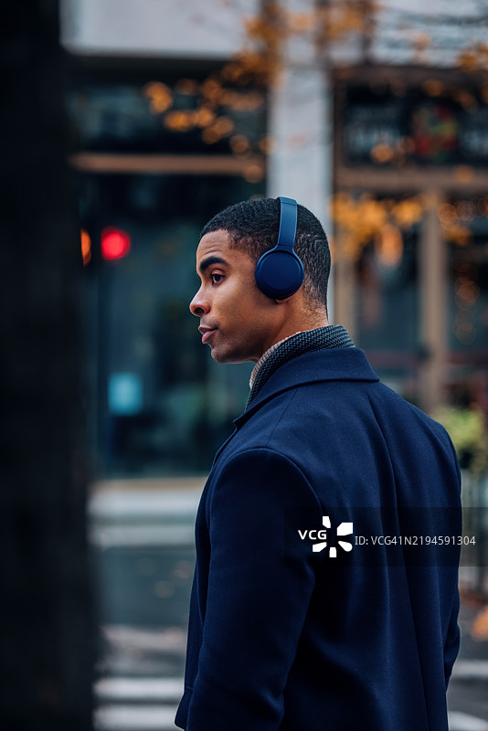 时尚男士在城市秋季户外环境中佩戴耳机图片素材