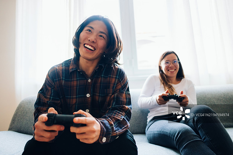 两个朋友在明亮的客厅里一起享受视频游戏的乐趣图片素材