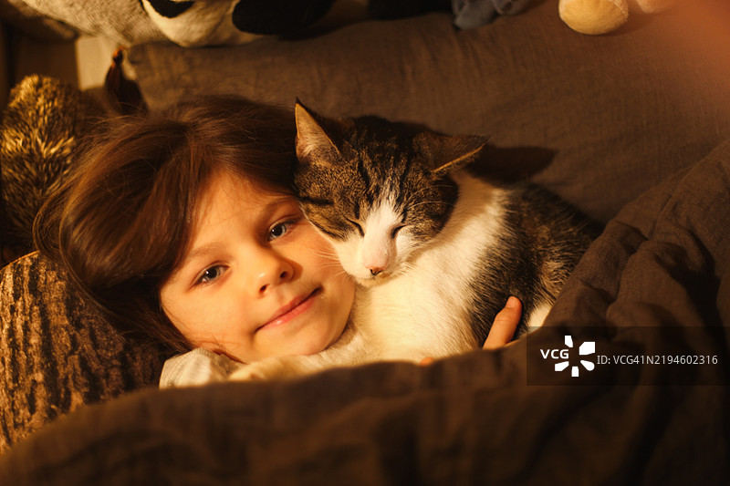 女孩在床上拥抱她的猫的肖像图片素材