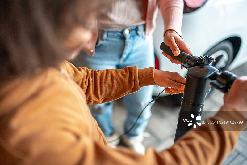 西班牙裔母亲与混血儿子一起调整电动滑板车图片素材
