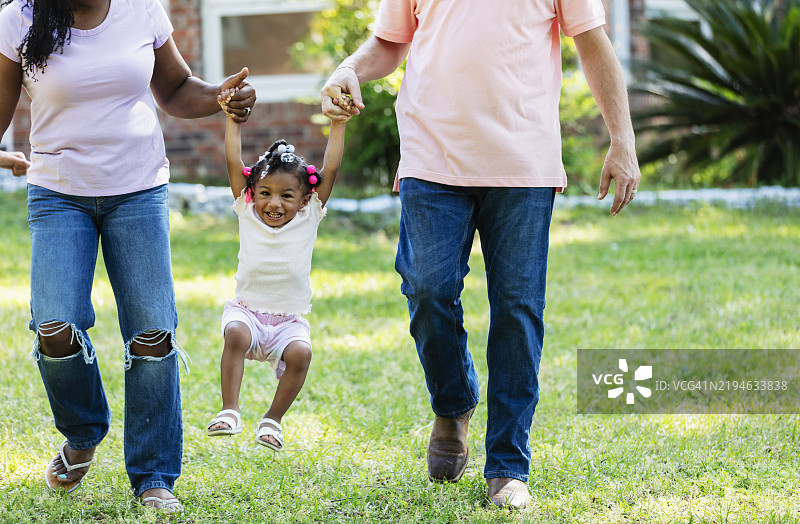 多种族父母在两人之间摇摆小女孩图片素材