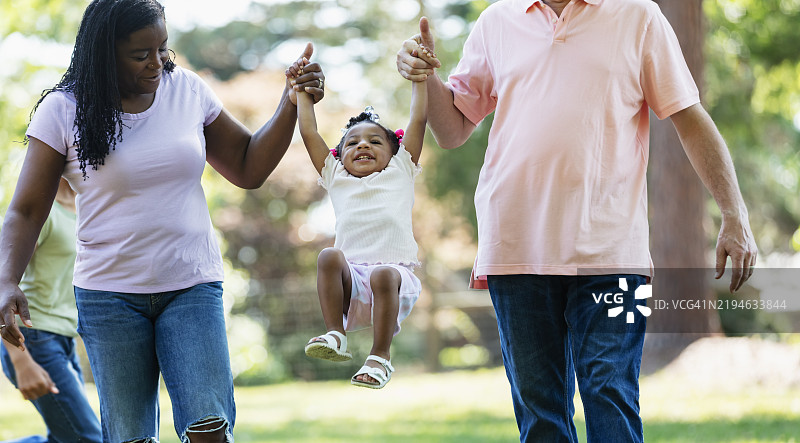 多种族父母在彼此之间摇摆小女孩图片素材