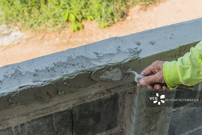 抹灰工正在装饰抹灰的边缘，在工艺语言中称为Jab xiiam，以实现美丽的抹灰效果。图片素材