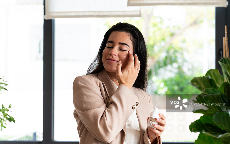 女商人在家办公室涂抹面霜图片素材