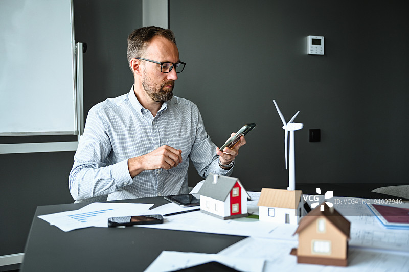 办公室里的建筑工程师思考房屋建设项目（智能手机）图片素材