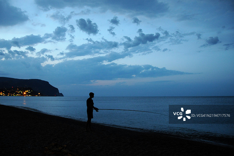 蓝色时刻与马切利海滩的渔夫。背景是科内罗山。图片素材