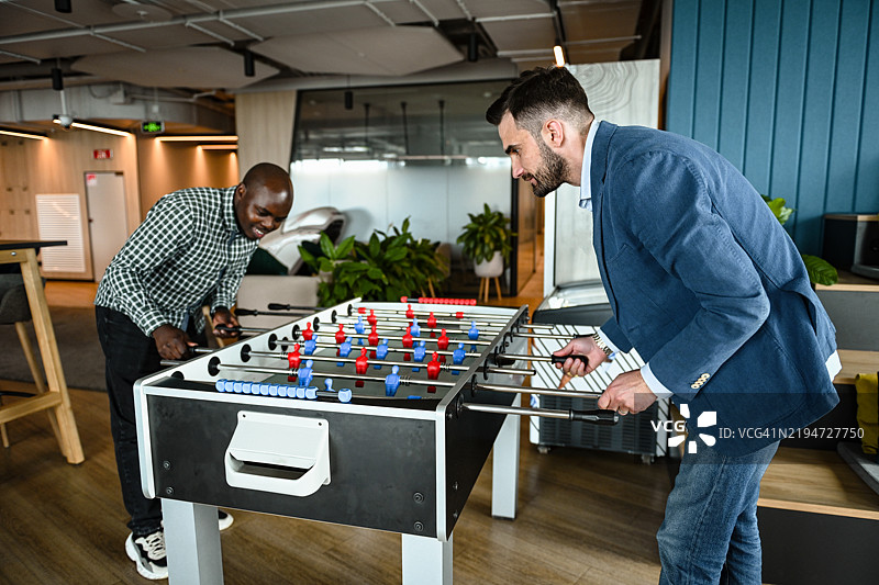 办公室里的商务朋友们在玩桌上足球图片素材
