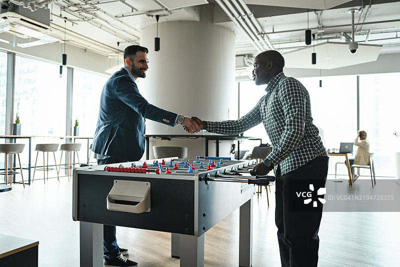 办公室里的商务朋友们在玩桌上足球图片素材