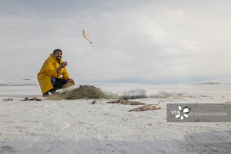 渔民在冬季的冰冻湖面上扔鱼图片素材