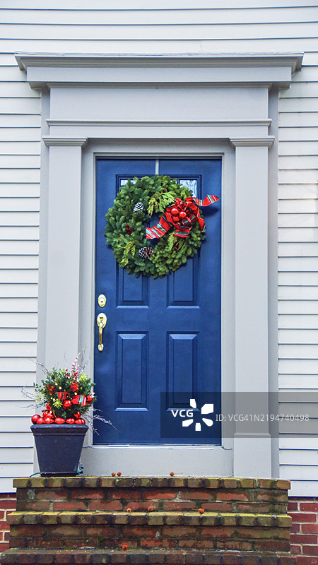 节日气氛的蓝色木门，装饰着圣诞装饰，背景是白色面板外立面图片素材