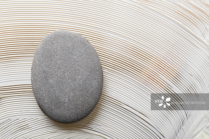 光滑的灰色石头放在有纹理的奶油色背景上图片素材