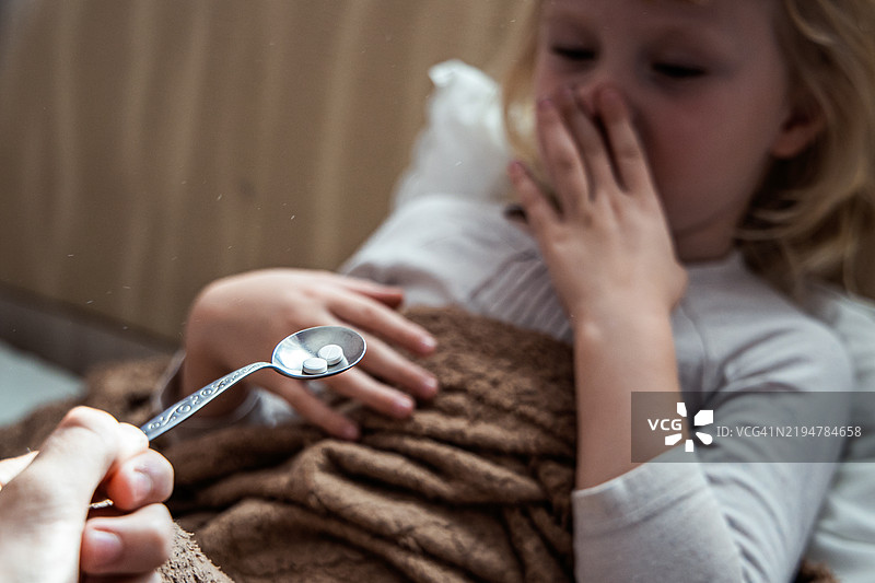 一个孩子在家安静的早晨躺在床上犹豫是否服药。图片素材