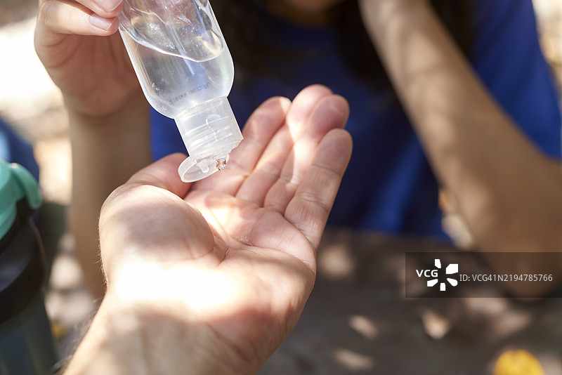 青少年在徒步旅行时将消毒凝胶倒入另一个人的手中图片素材