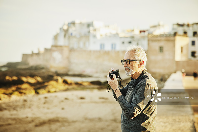 中景宽镜头的老年男子在日出时拍摄埃索伊拉的照片图片素材