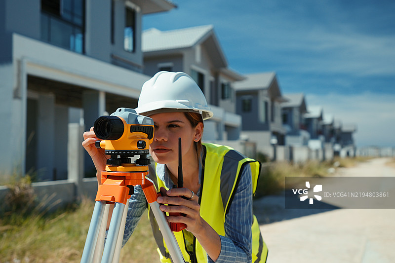 女性测量员在住宅施工现场使用经纬仪测量土地图片素材