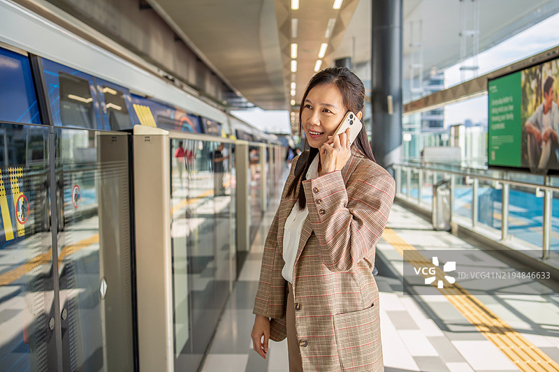 女性在前往地铁的路上使用智能手机拨打电话图片素材