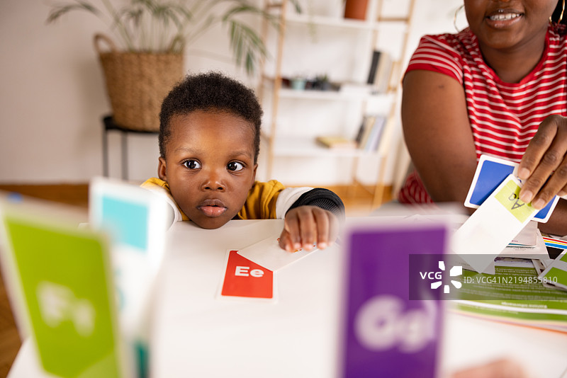 好奇的黑人孩子在玩字母闪卡，学习字母表图片素材
