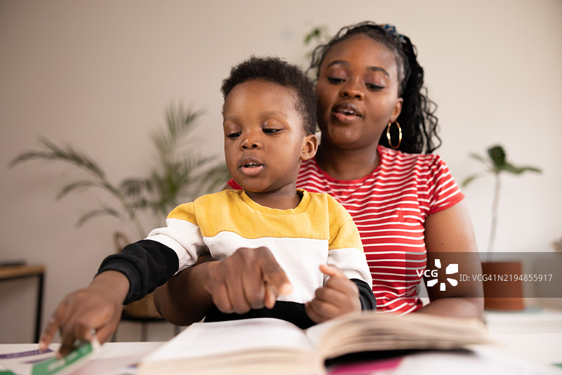 母亲在家帮助儿子阅读书籍和学习图片素材