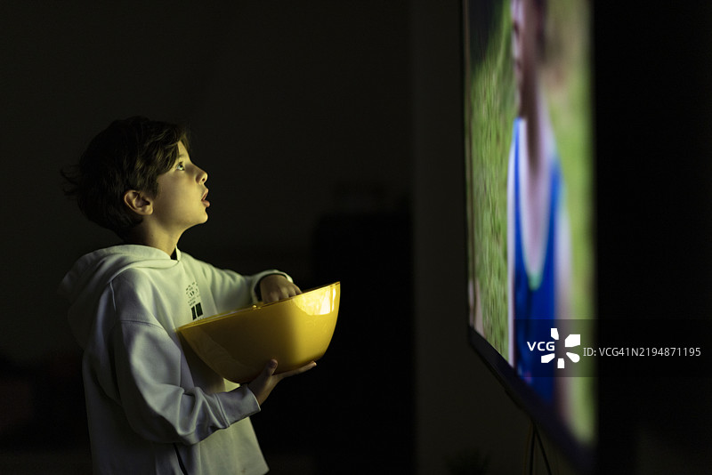 孩子在家看电影时享受爆米花图片素材