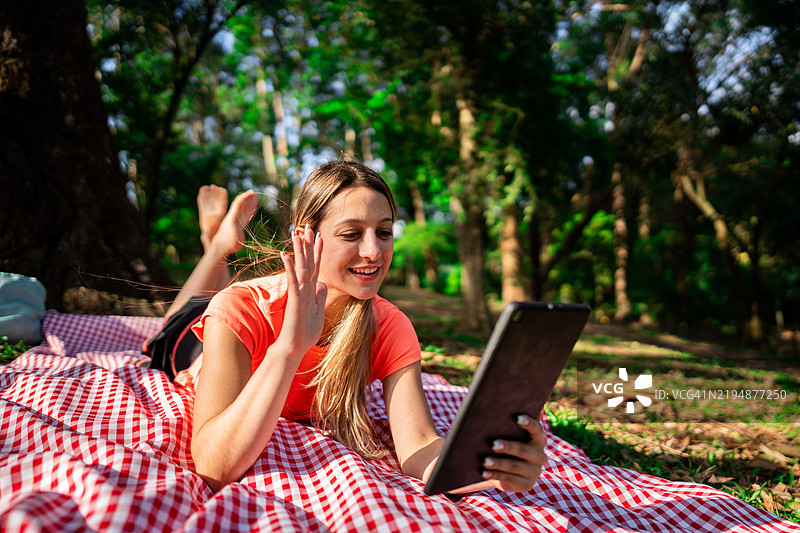 年轻女性在公园里用平板电脑进行视频通话图片素材