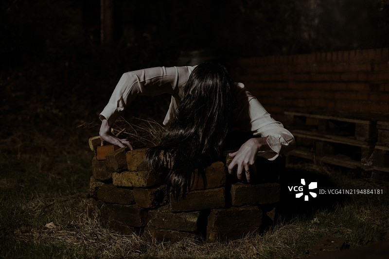 万圣节装扮成《午夜凶铃》中贞子的角色从井里爬出来的人图片素材