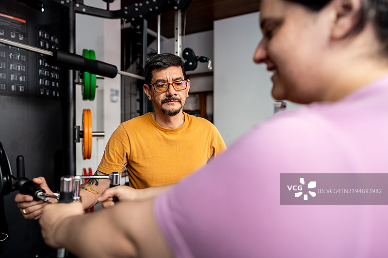 健身教练在健身房帮助学生锻炼图片素材