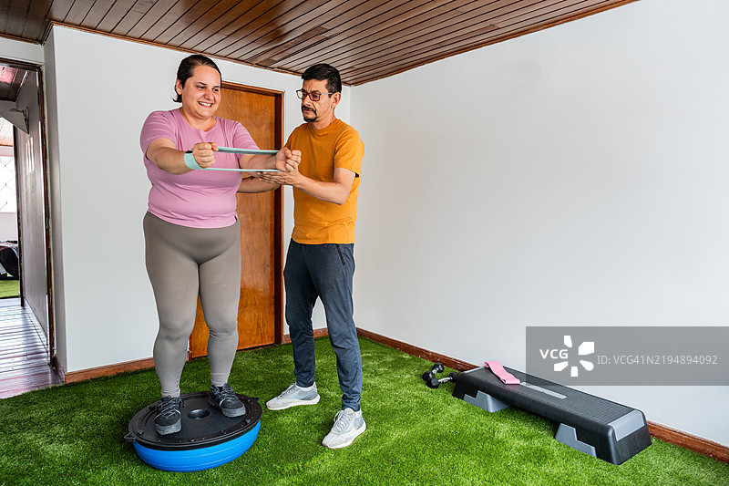 健身教练在健身房帮助学生练习本体感觉训练。图片素材