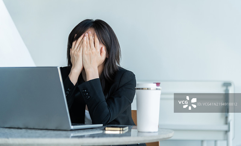 疲惫的女商人用双手捂住脸。图片素材