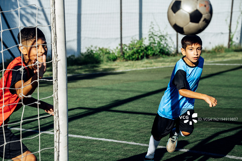 孩子们在球场上踢足球，积极参与体育活动图片素材
