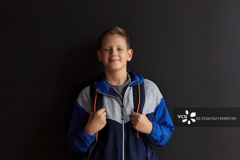 黑色墙壁前的少年，具有高对比度的留白空间图片素材