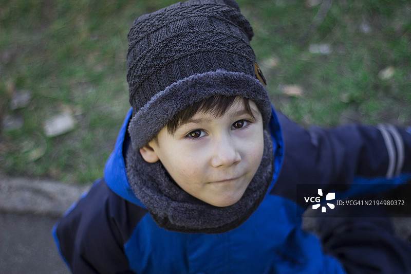 一个穿着蓝色雪服的孩子坐在地上看着镜头图片素材