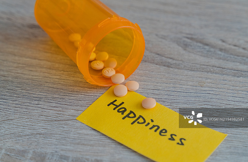 处方瓶旁边洒落的药丸和一张快乐的便条图片素材